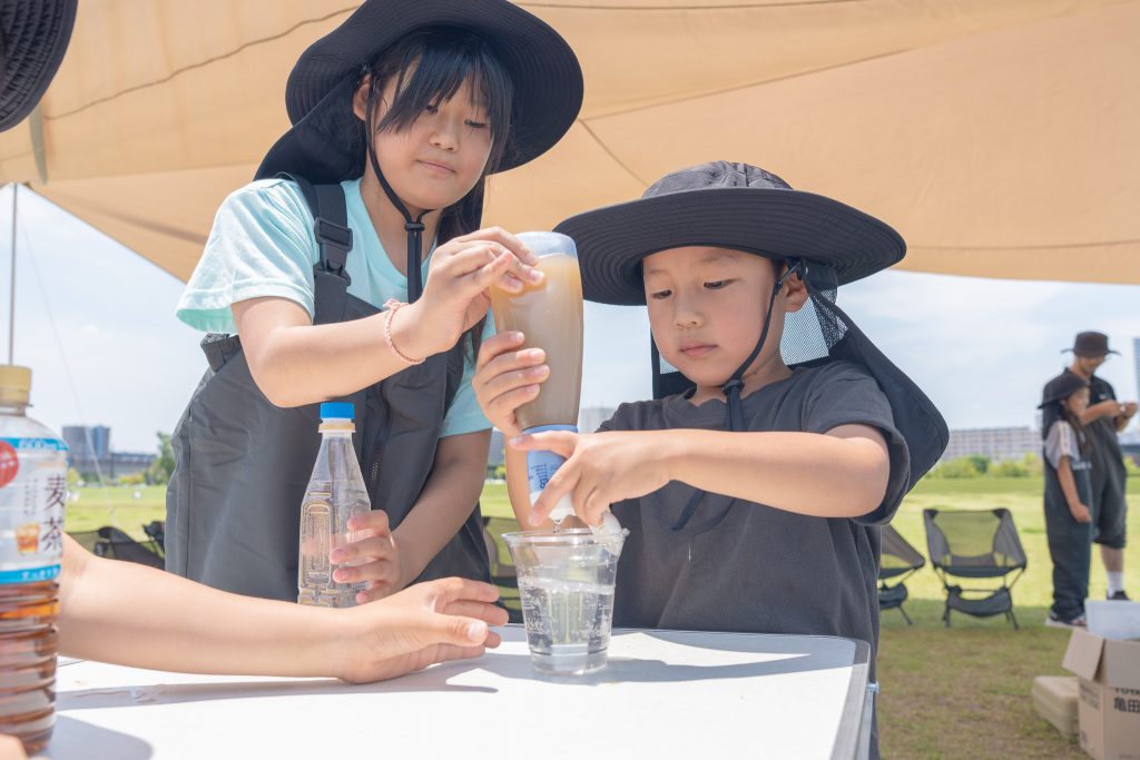 子供たちが携帯浄水器スーパーデリオスを使って防災体験をしている様子
