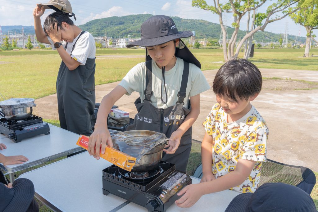 スーパーデリオスで泥水をろ過する実験をする子供たち